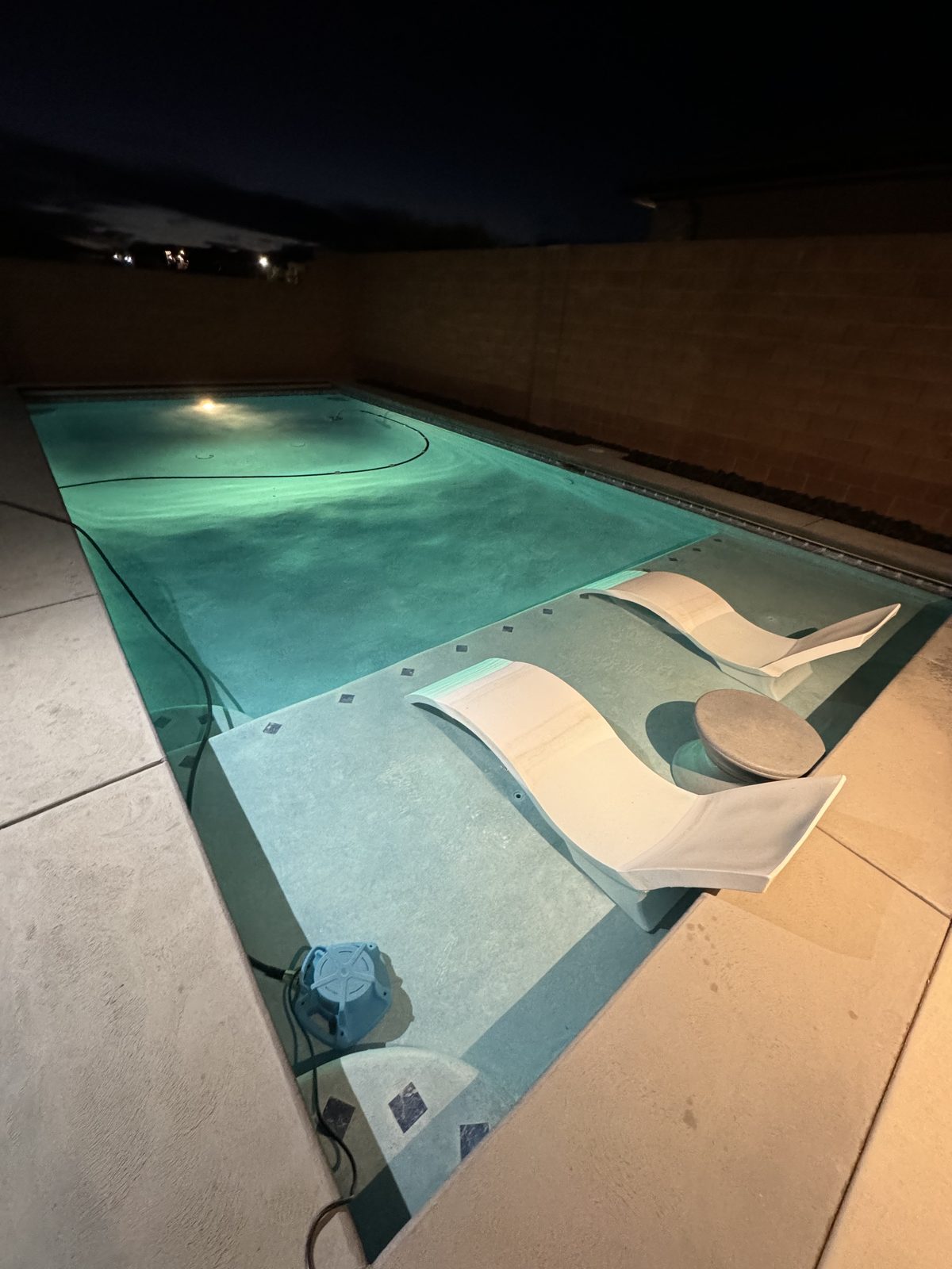 Pool lit at twilight with in-water loungers